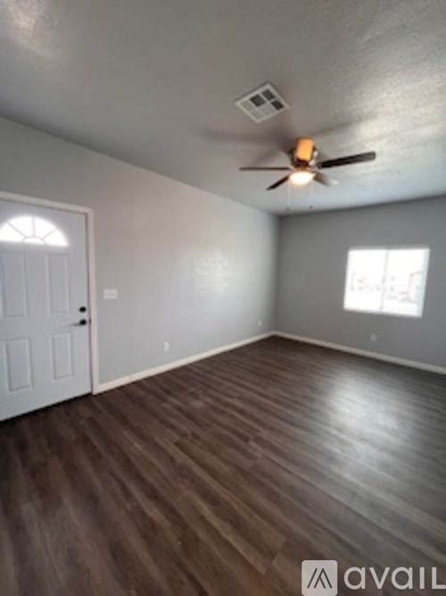 A room with a ceiling fan and wooden flooring.
