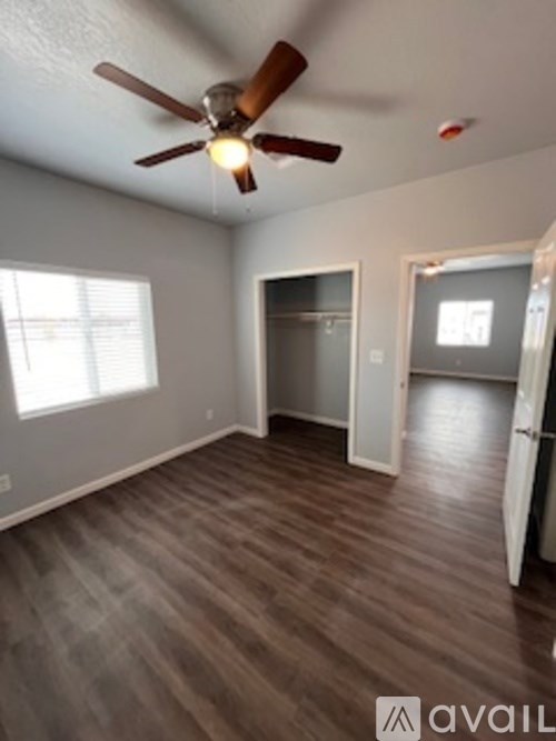 A room with a ceiling fan and wooden flooring.