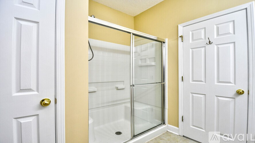 A bathroom with a walk-in shower and two white doors.