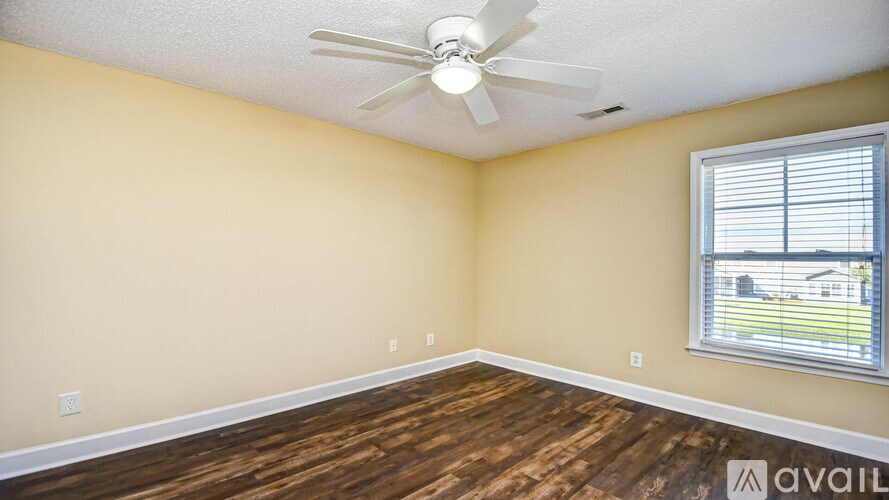 A room with a ceiling fan and wooden flooring.