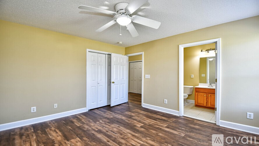 A room with a ceiling fan and a view into a bathroom.