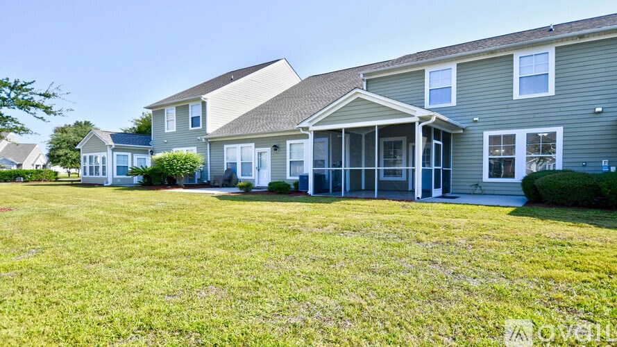 A grassy lawn in front of a two-story house with a covered patio.