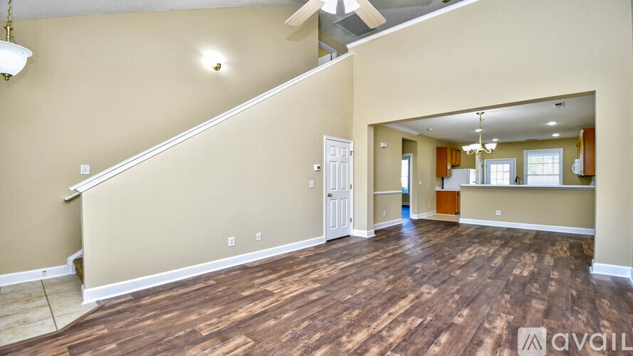 A spacious room with wooden floors and a staircase leading to another level.