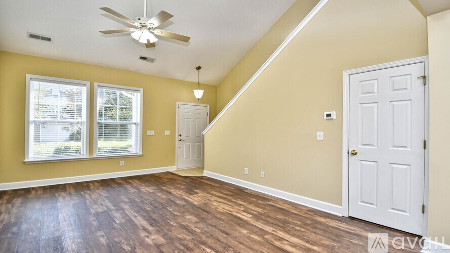 A room with a white door and a ceiling fan.