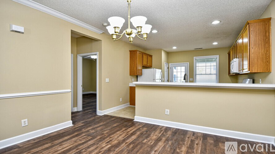 A kitchen area with wooden floors and a chandelier.