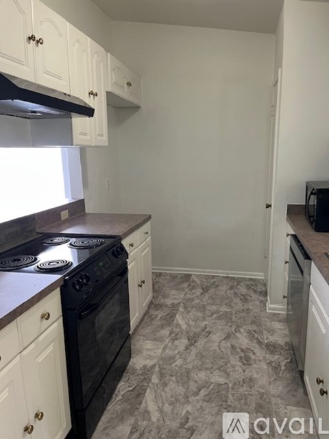 A kitchen with a black stove top oven and white cabinets.