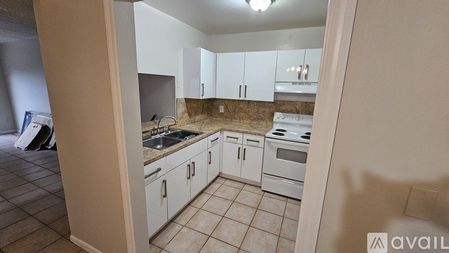 A kitchen with white cabinets and appliances is available for rent.