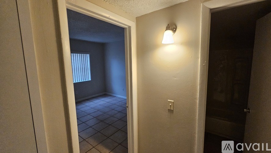 A hallway with a light on the wall and a door at the end.