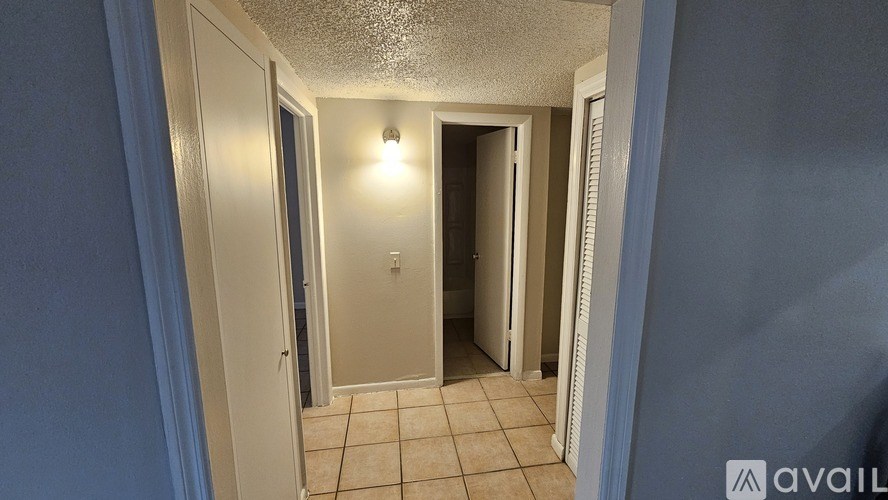 A hallway with a light on and tiled floors.