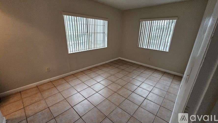 A room with tiled flooring and two windows.