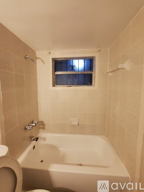 A bathroom with a toilet, tub, and window.