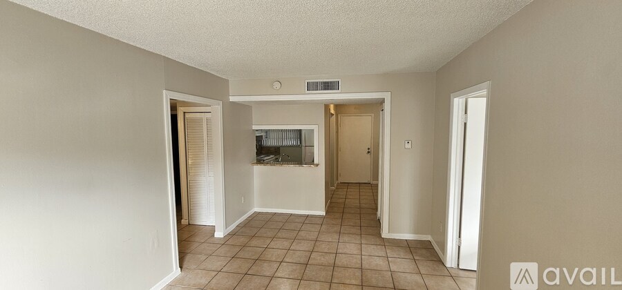 A spacious room with tiled flooring and a window with blinds.