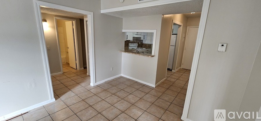 A living room with a tiled floor and a kitchen area in the background.