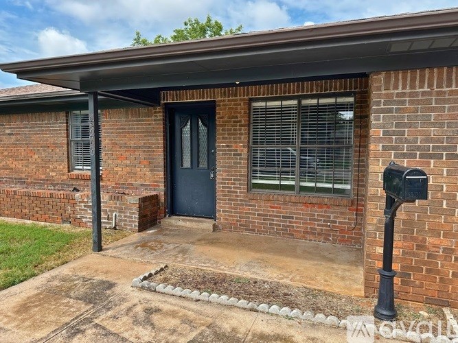 A brick house with a black door and mailbox.