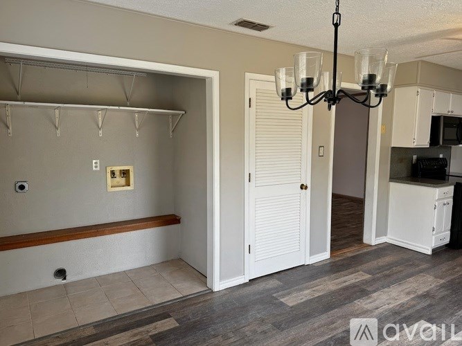 A room with a chandelier, a cabinet, and a bench.