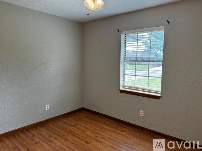 A room with a window and wooden flooring.