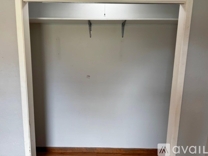 A white wall with a wooden frame and a small black object hanging from the top.