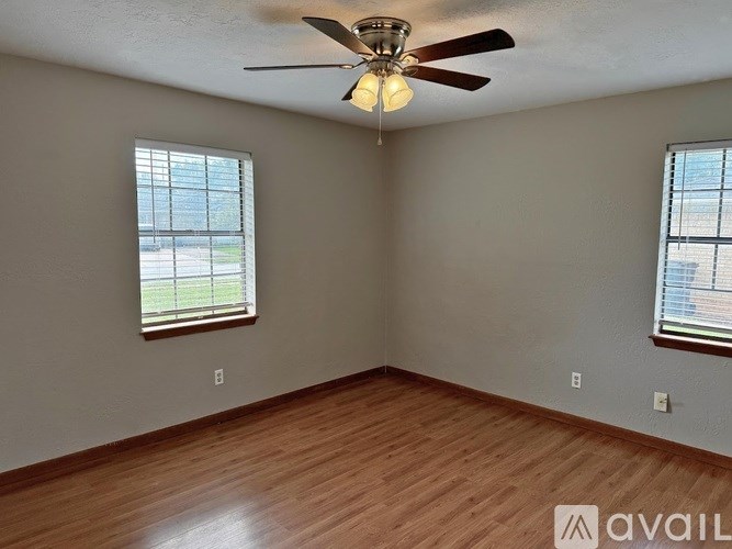 A room with a ceiling fan and two windows.