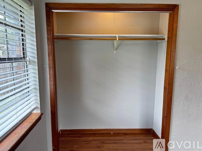 A wooden closet with a white door and a window with blinds on the left side.