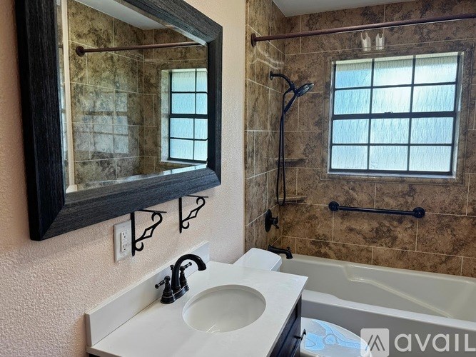 A bathroom with a sink, mirror, and bathtub.