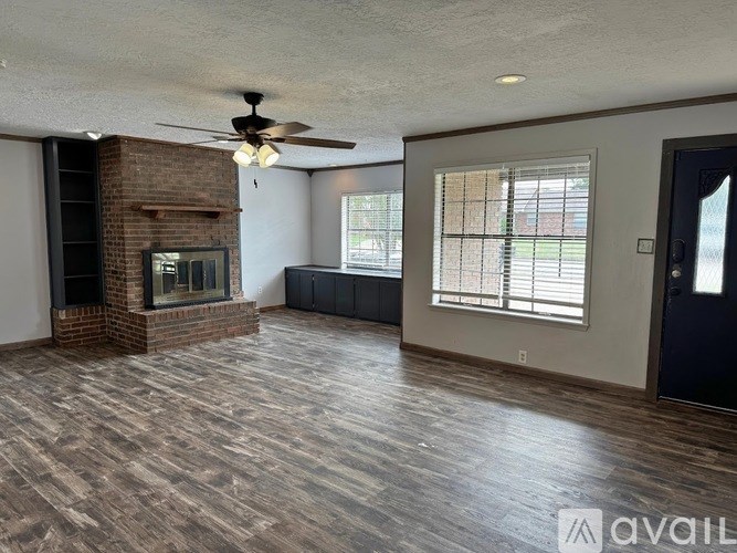 A living room with a brick fireplace and hardwood floors.
