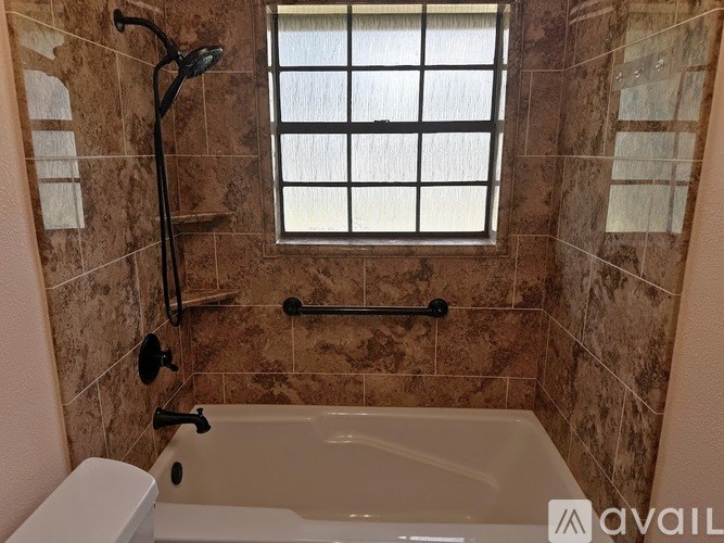 A bathroom with a tiled wall and a window.