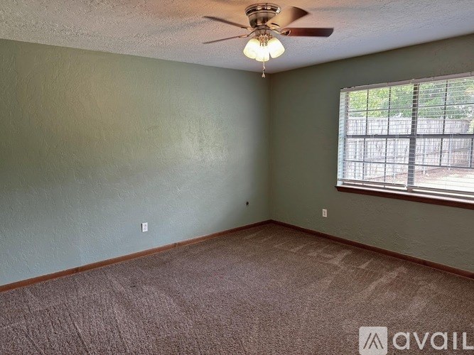 A room with a ceiling fan and a window with bars.
