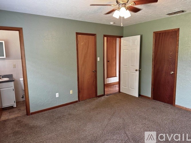 A room with a carpeted floor and a ceiling fan.