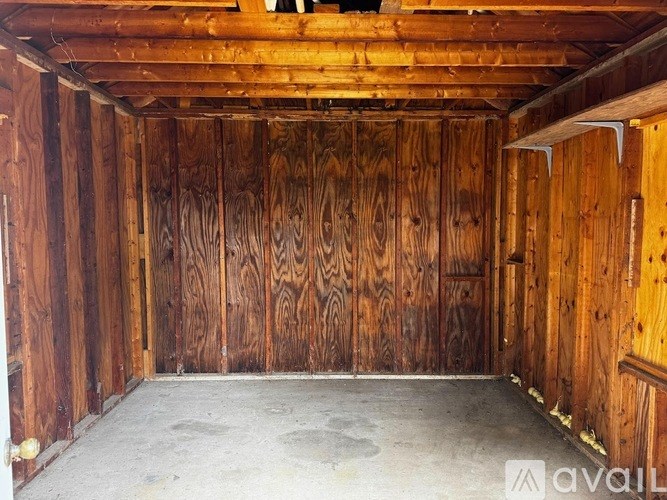 A wooden room with a concrete floor and a ceiling with wooden beams.