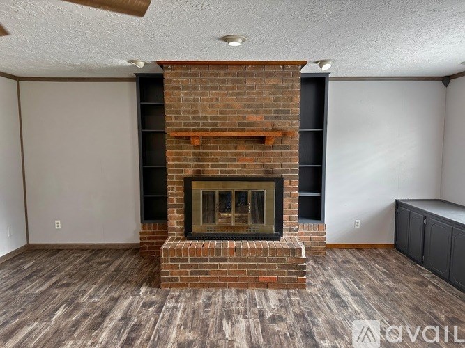 A room with a brick fireplace and wooden flooring.