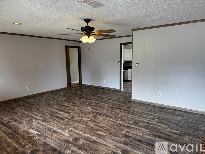 A room with a ceiling fan and wood flooring.