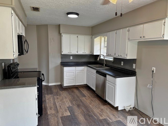 A kitchen with white cabinets and a black countertop.