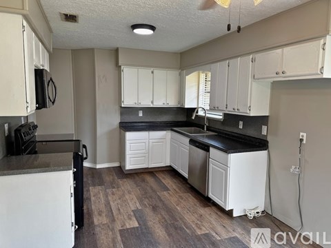 A kitchen with white cabinets and a black countertop.
