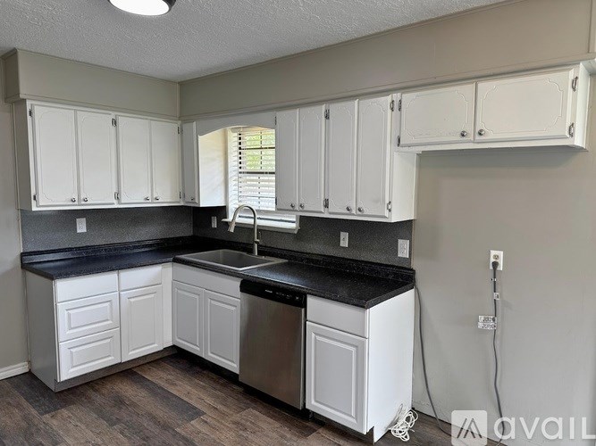 A kitchen with white cabinets and a black countertop.