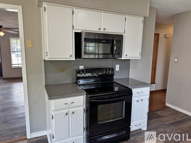 A kitchen with white cabinets and a black stove top oven.