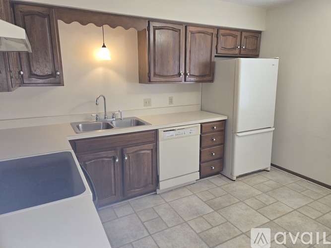A kitchen with brown cabinets and a white fridge.