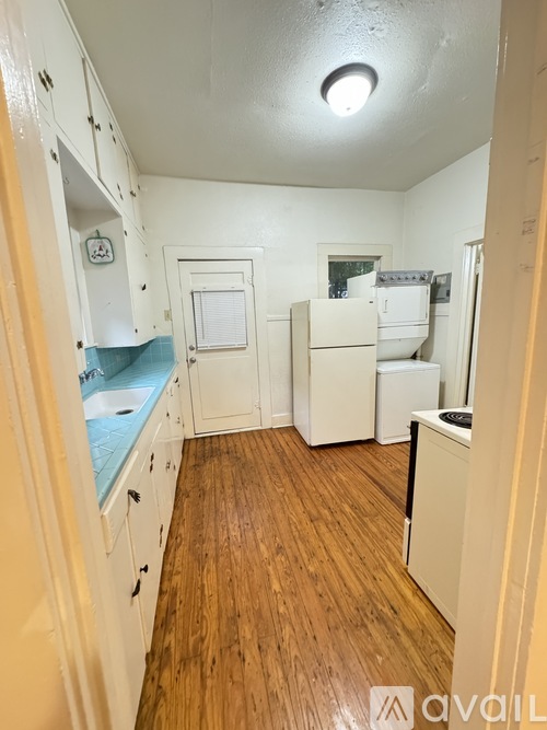 A kitchen with wooden floors and white cabinets.
