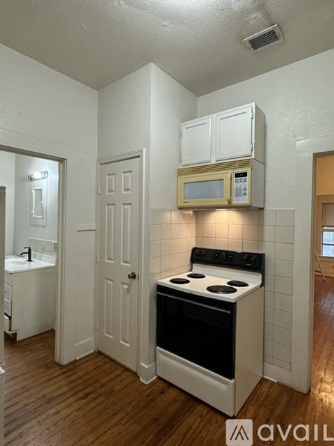 A kitchen with a stove, sink, and microwave.