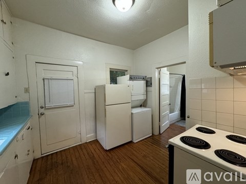 A kitchen with white appliances and wooden floors.