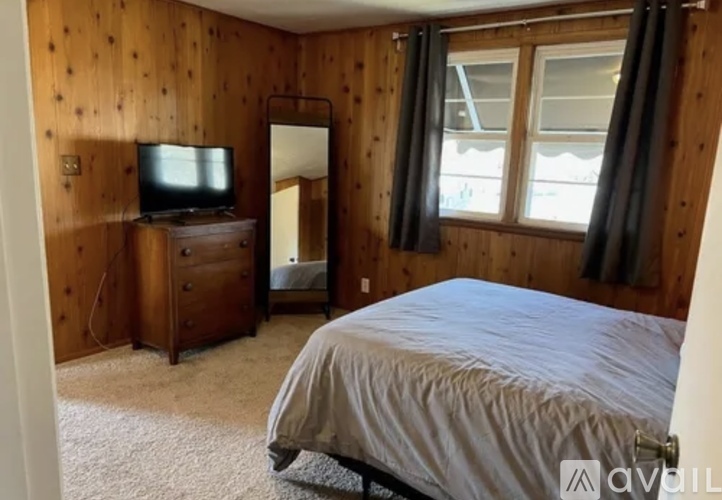 A bedroom with a bed, dresser, and television.