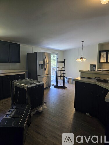 A kitchen with black cabinets and a refrigerator with a stove on top.
