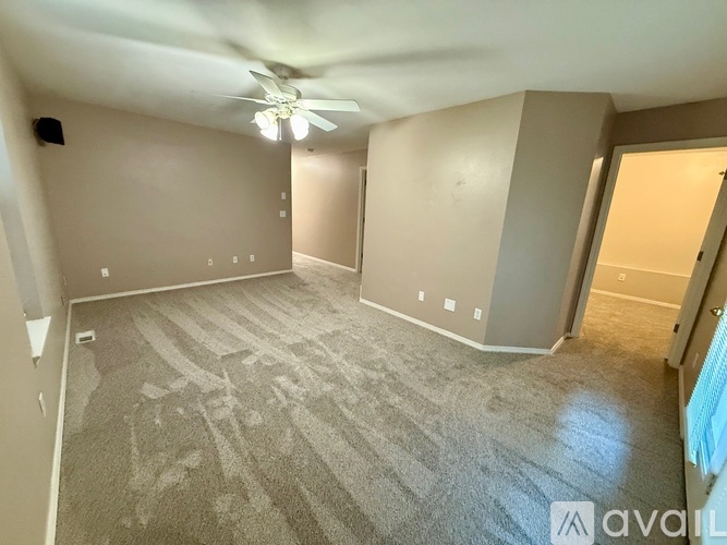 A spacious room with a carpeted floor and a ceiling fan.
