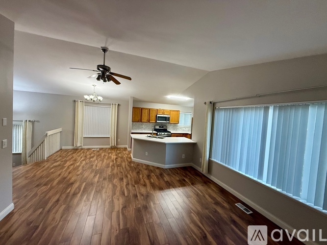 A spacious room with wooden flooring and a ceiling fan.