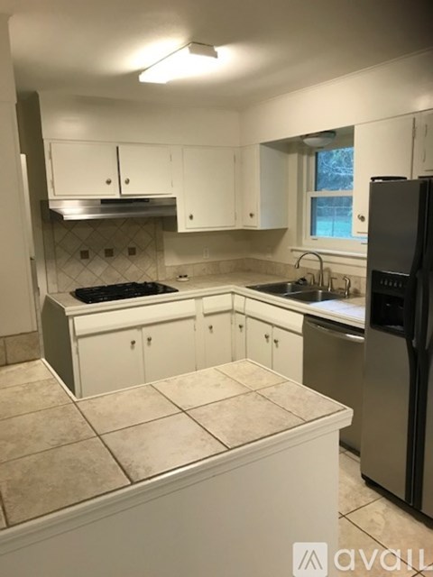 A kitchen with white cabinets and a black refrigerator.