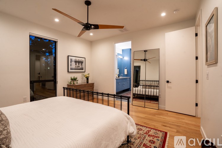 A bedroom with a bed, a ceiling fan, and a mirror.