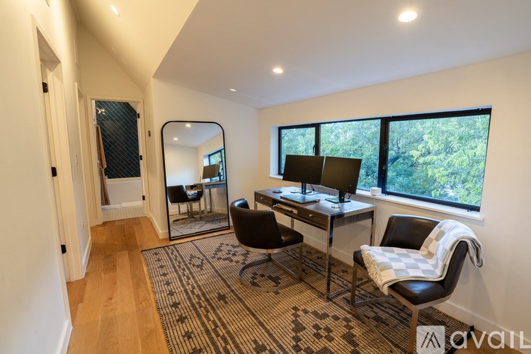 A room with a desk and chairs with a mirror on the wall.