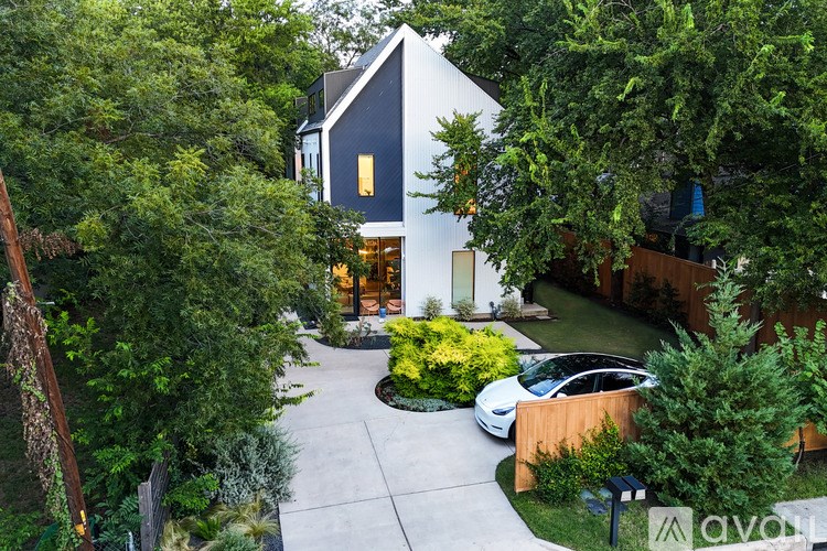 A modern house with a large front yard and a driveway.