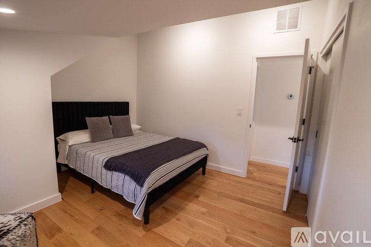 A bedroom with a bed, pillows, and a wooden floor.