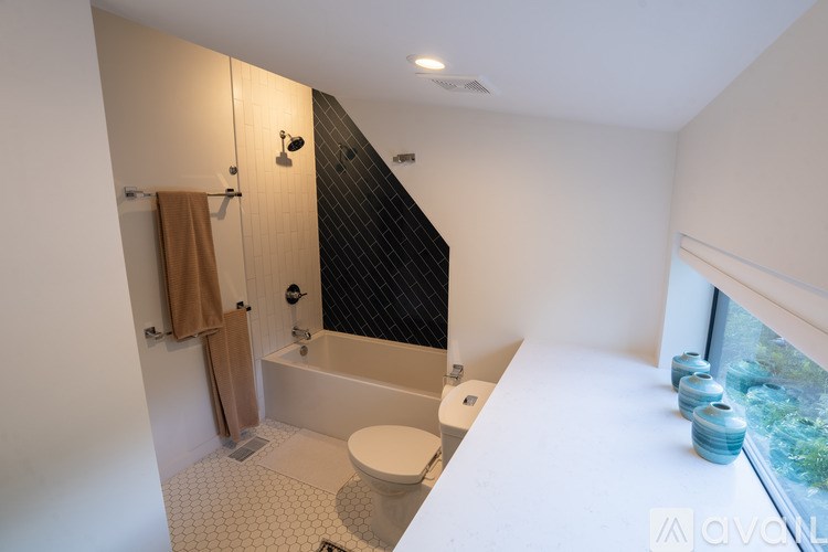 A bathroom with a toilet, a bathtub, and a window.