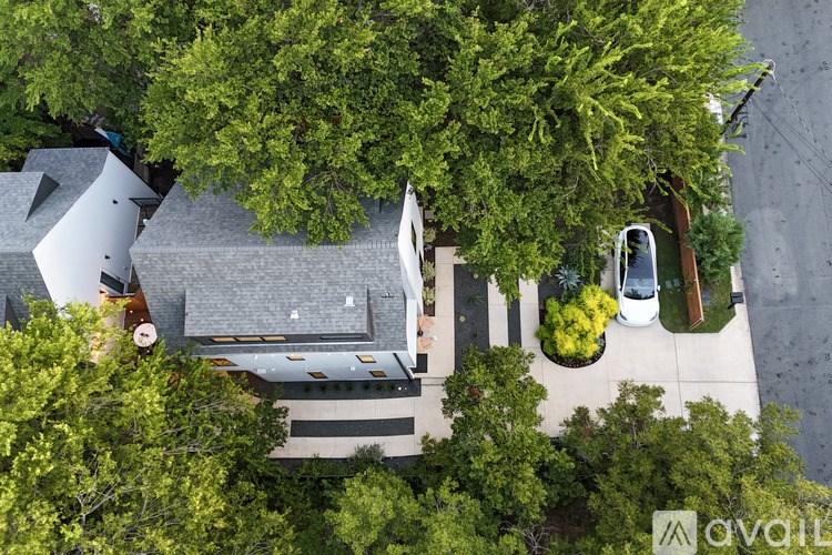A bird's eye view of a house surrounded by trees and a car parked in the driveway.